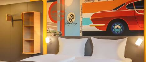 Una habitación de hotel con una cama, una mesita de noche, un estante y un cartel de un auto de carreras en la pared.