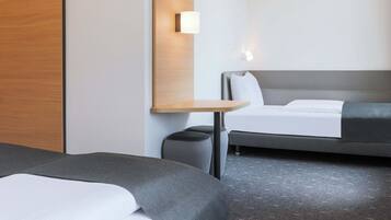 Una habitación de hotel con cama, mesita de noche, silla y sofá.