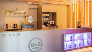 Un área de recepción con el logotipo de B&B Hotels, un mostrador de recepción y una exhibición de bebidas embotelladas.