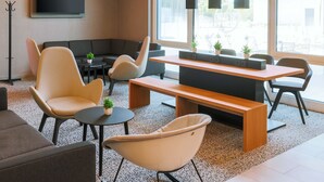 Un espacio de sala moderno con un sofá, sillas, una mesita de centro y un banco de madera.