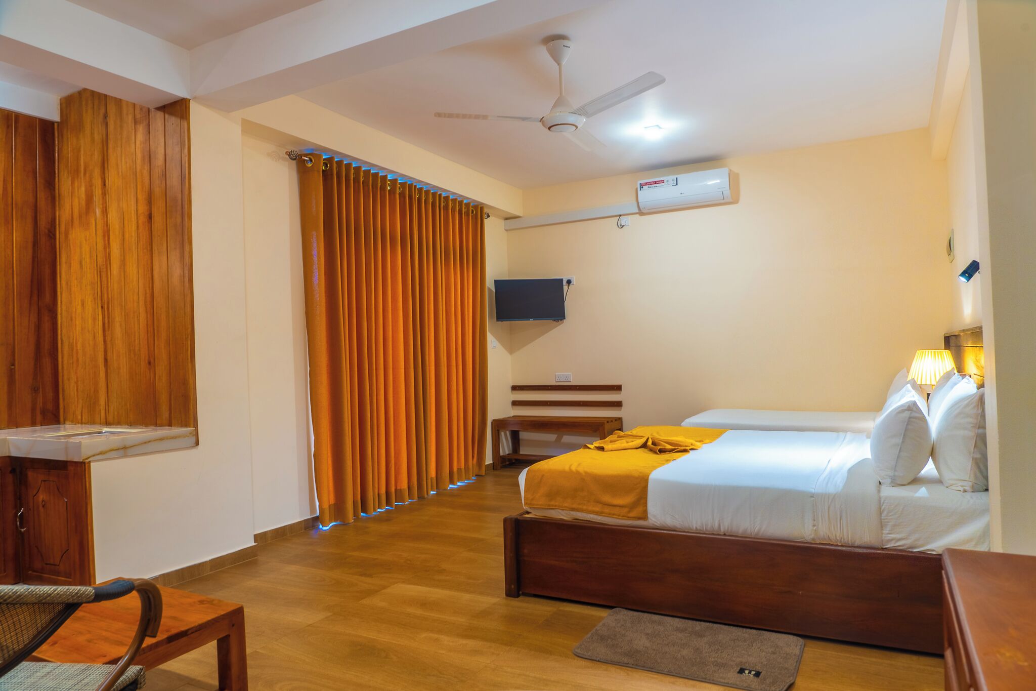 A hotel room with a bed, a desk, a chair, a television, and a ceiling fan.