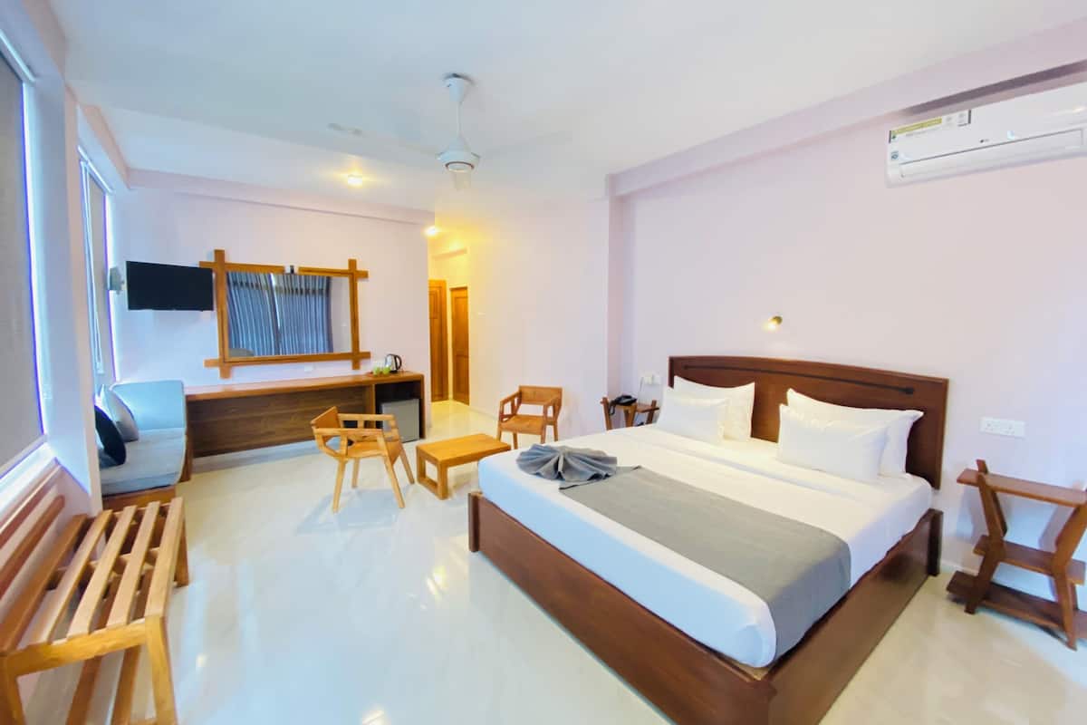 A hotel room with a bed, wooden furniture, a desk, and a TV.