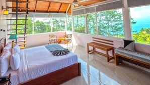 A bedroom with a bed, a bench, a sofa, a ladder, and a view of the ocean. - Mount Hunt Resort (Beragala)