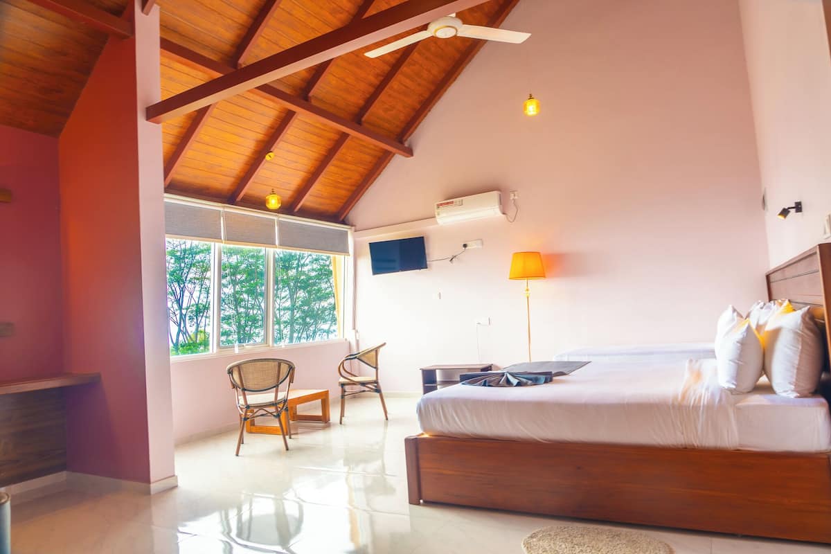 A bedroom with a wooden ceiling, a bed, a desk, and a chair.