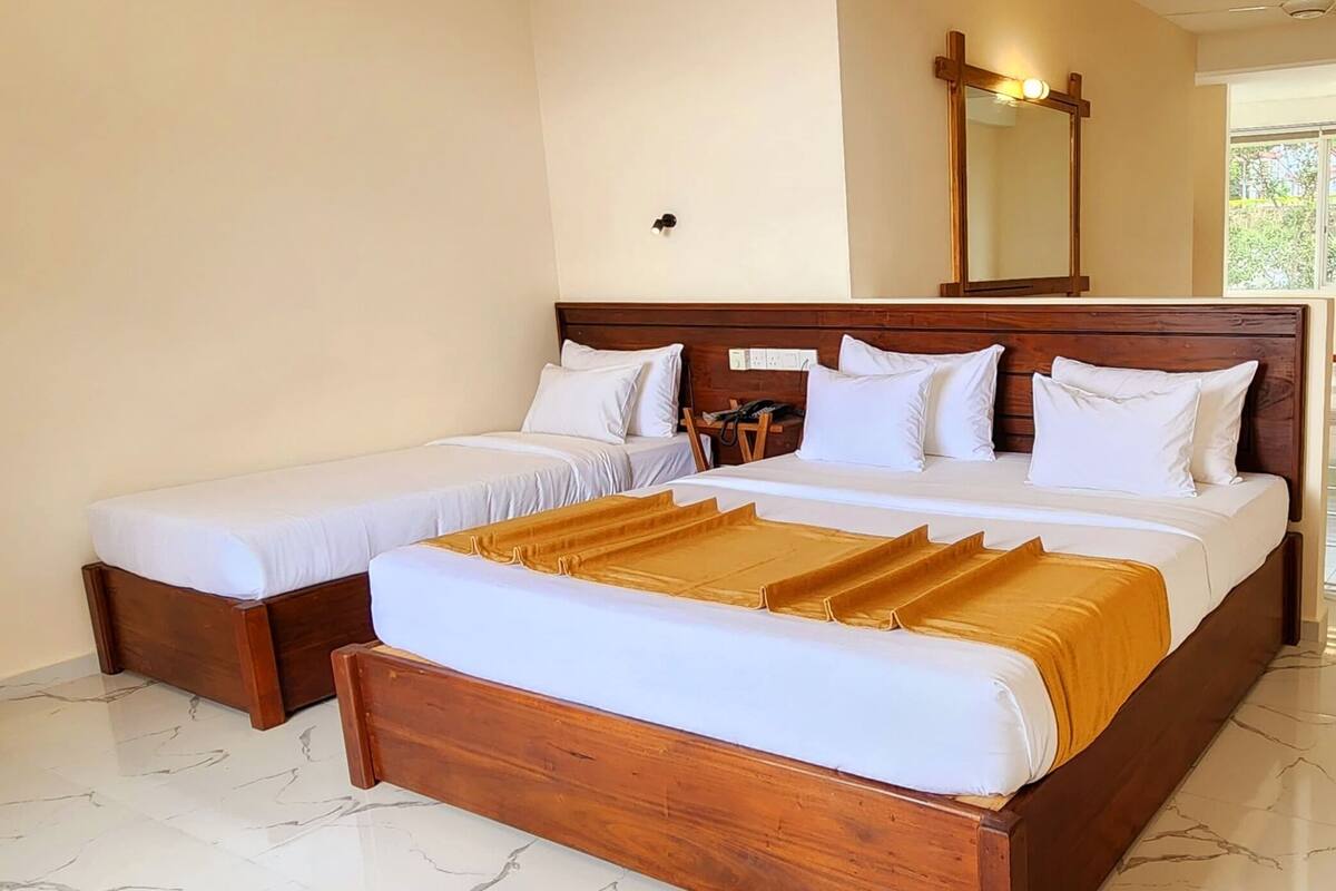 A double bed with a wooden headboard and a single bed to the left.