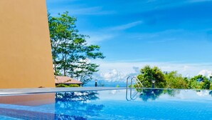 A clear blue infinity pool with a tiled edge, surrounded by greenery and a clear sky. - Mount Hunt Resort (Beragala)