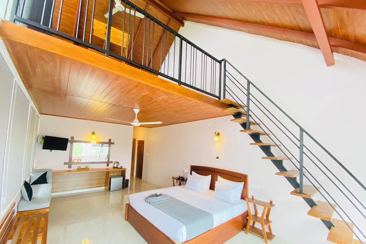 A bedroom with a wooden bed, a desk, a chair, a staircase, and a ceiling fan.