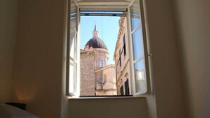 A room with a bed and a window overlooking a building with a dome. - La Dolce Vita-Old Town (Dubrovnik)