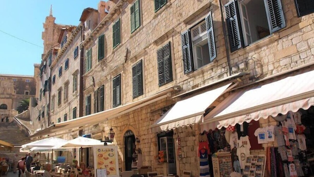 A street with outdoor seating, stone buildings, and shops. - La Dolce Vita-Old Town (Dubrovnik)