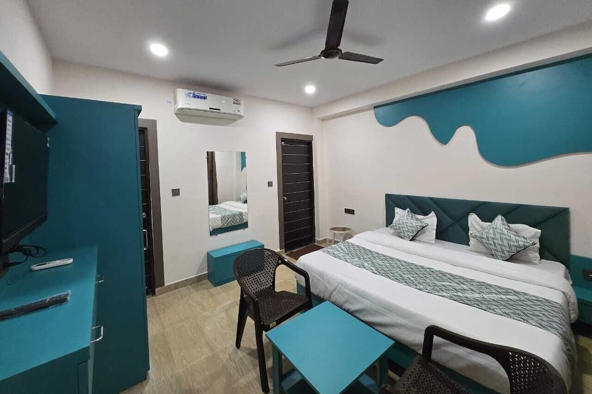 A hotel room with a bed, a desk, a chair, a TV, and a ceiling fan.