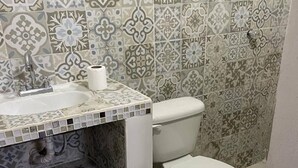 A bathroom with a sink, toilet, and patterned tiles.