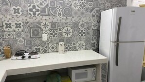 A kitchen with patterned tiles, a white countertop, a stove, a microwave, and a refrigerator.