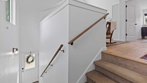 A staircase with wooden handrails, a light-colored wall, and a door with a wreath.
