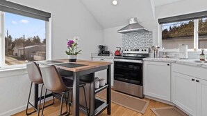 A modern kitchen with a dining area, large windows, and a view of the outside. - Stylish couples retreat near lake and downtown (Coeur d'Alene)