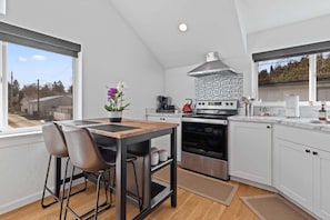 A modern kitchen with a dining area, large windows, and a view of the outside. - Stylish couples retreat near lake and downtown (Coeur d'Alene)