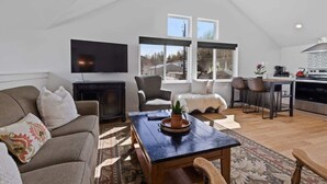 A loft-style living space with a dining area, kitchen, and a large window providing natural light.