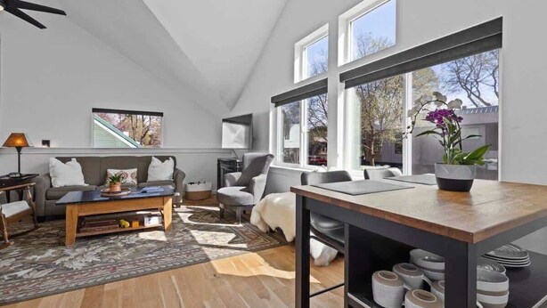 A modern living room with a sofa, coffee table, and a dining table with a vase of flowers.