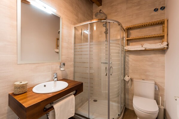 A modern bathroom with a glass-enclosed shower, a wooden vanity with a sink, and a toilet. - El Balcon de La Lomba - Casa (Hermandad de Campoo de Suso)