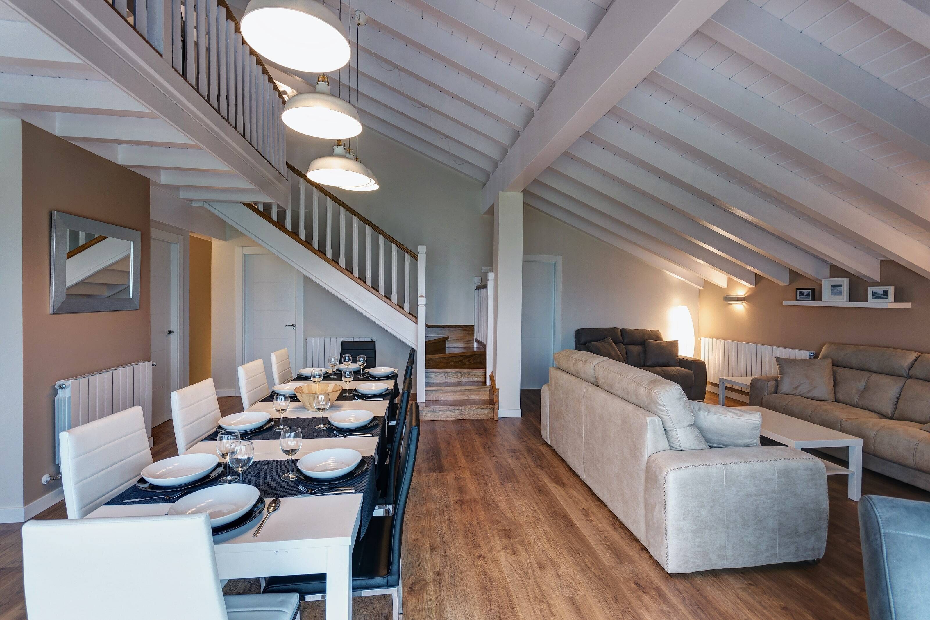 A spacious loft with a dining area, a living room, and a staircase.