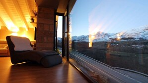 Un interno moderno con una grande finestra che si affaccia su un paesaggio innevato e un binario ferroviario.