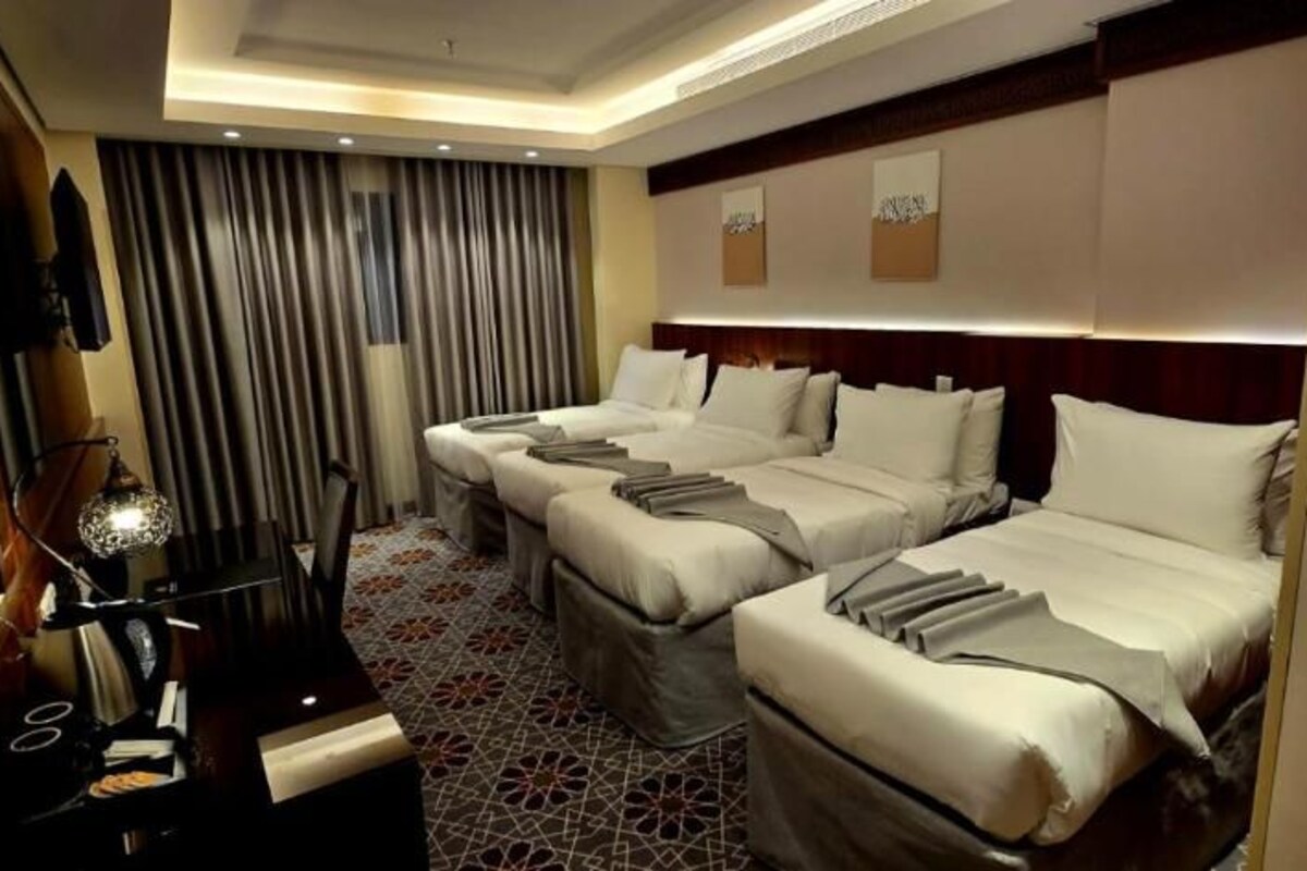 A hotel room with two beds, a desk, and a mirror.