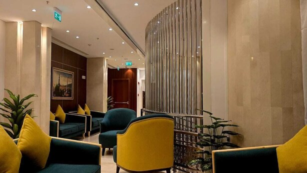 Eine moderne Lobby mit Sitzbereichen, einem Feuerlöscher und einer Treppe.