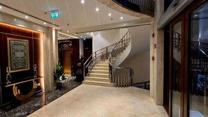 Eine moderne Hotelhalle mit Marmorboden, einer geschwungenen Treppe und einer großen Wanddekoration.