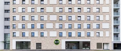 A multi-story hotel building with a modern facade, featuring a prominent 'HOTEL' sign at the top and 'B&B HOTELS' branding on the windows.