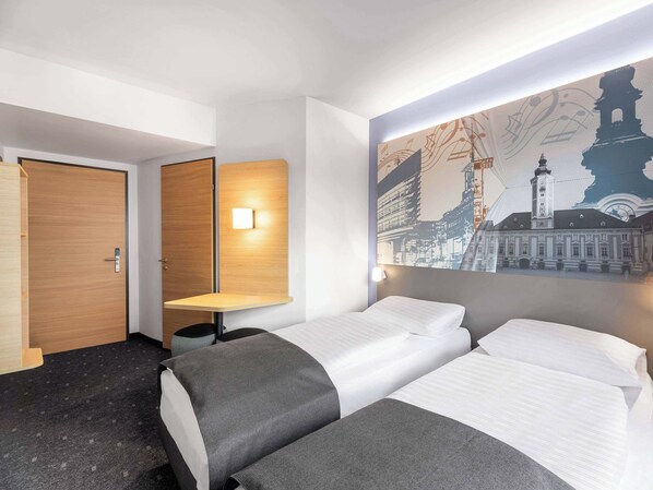 A hotel room with two beds, a desk, and a wall-mounted light. - B&B HOTEL St. Pölten (St. Pölten)