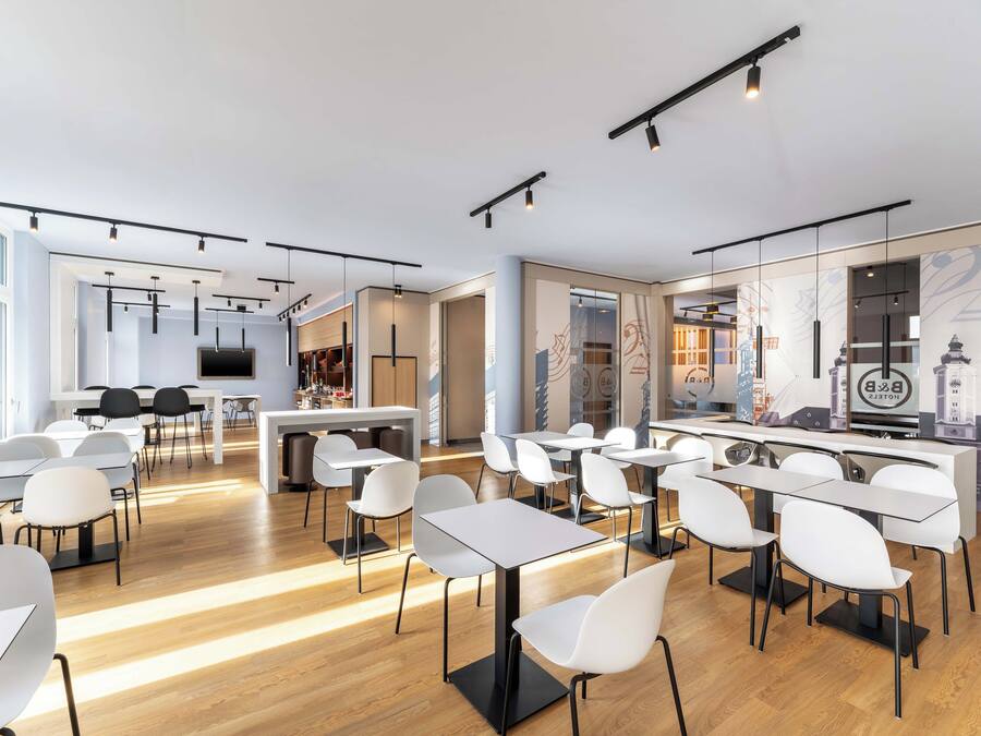 A modern hotel lobby with a bar area, seating arrangements, and a large screen.