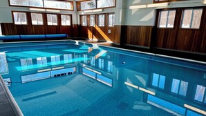 An indoor swimming pool with clear blue water, wooden paneling, and multiple windows. - SkiBoltonValleyVTPresWkFeb12-19Slopeside1bdrm2bthSteSlps8 (Richmond)