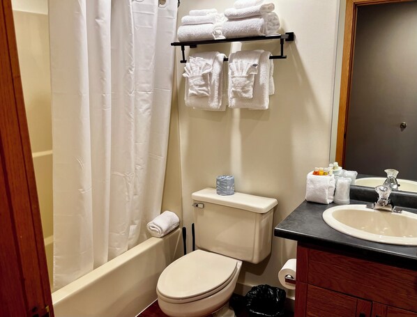 A bathroom with a toilet, sink, and a towel rack with folded towels.