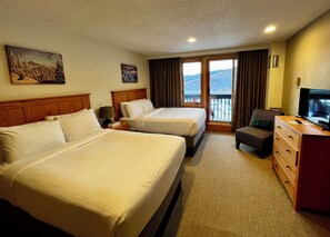 A hotel room with two beds, a television, a dresser, and a balcony with a view.