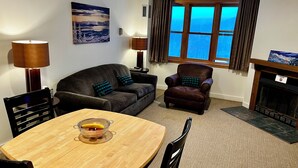 A living room with a sofa, armchair, dining table, and a fireplace. - SkiBoltonValleyVTPresWkFeb12-19Slopeside1bdrm2bthSteSlps8 (Richmond)