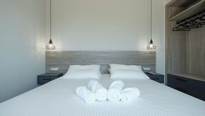 Une chambre d’hôtel moderne avec un lit bien fait, deux tables de chevet et une armoire en bois.