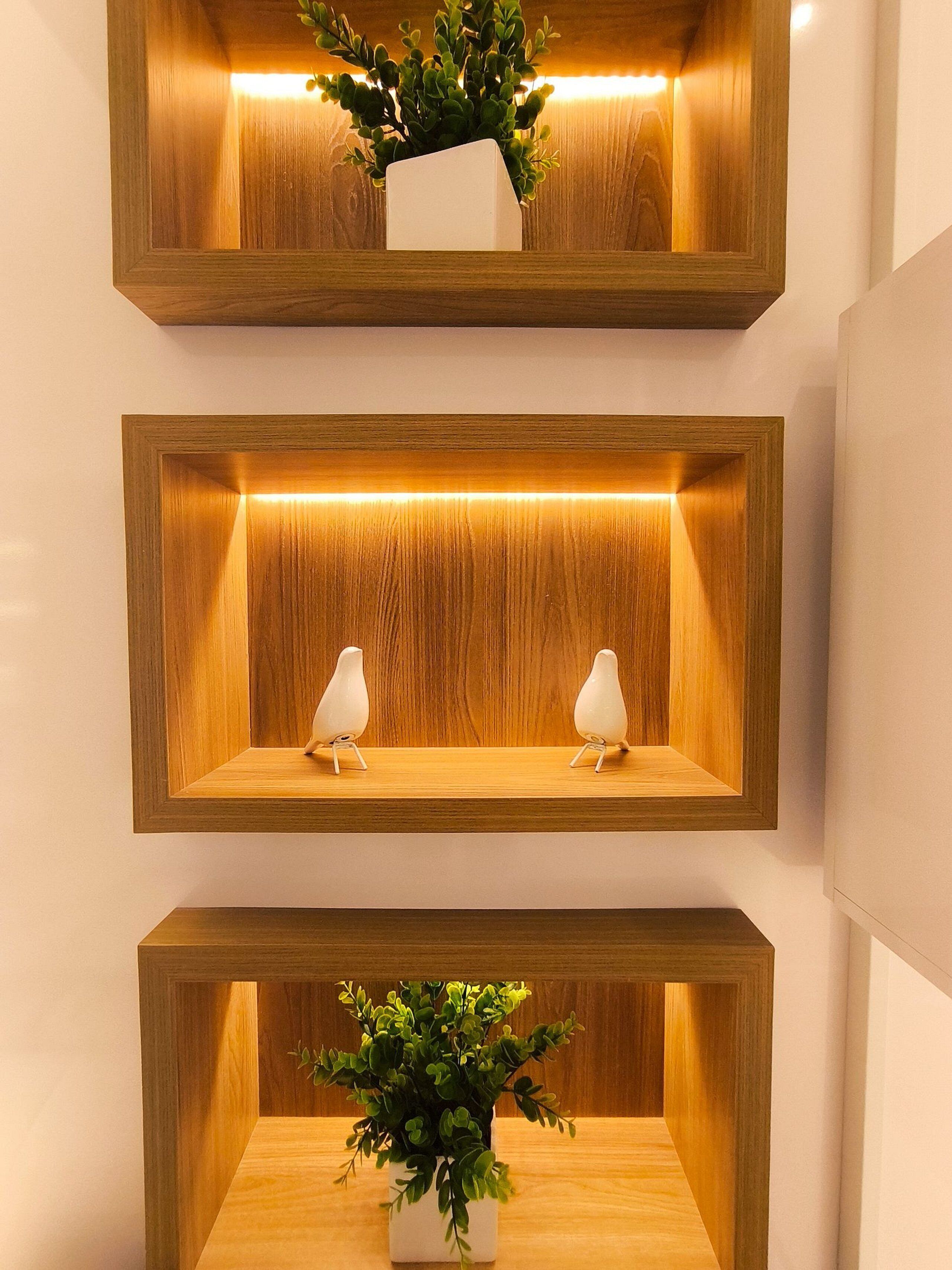 Three wooden shelves with plants and two white bird-shaped sculptures.
