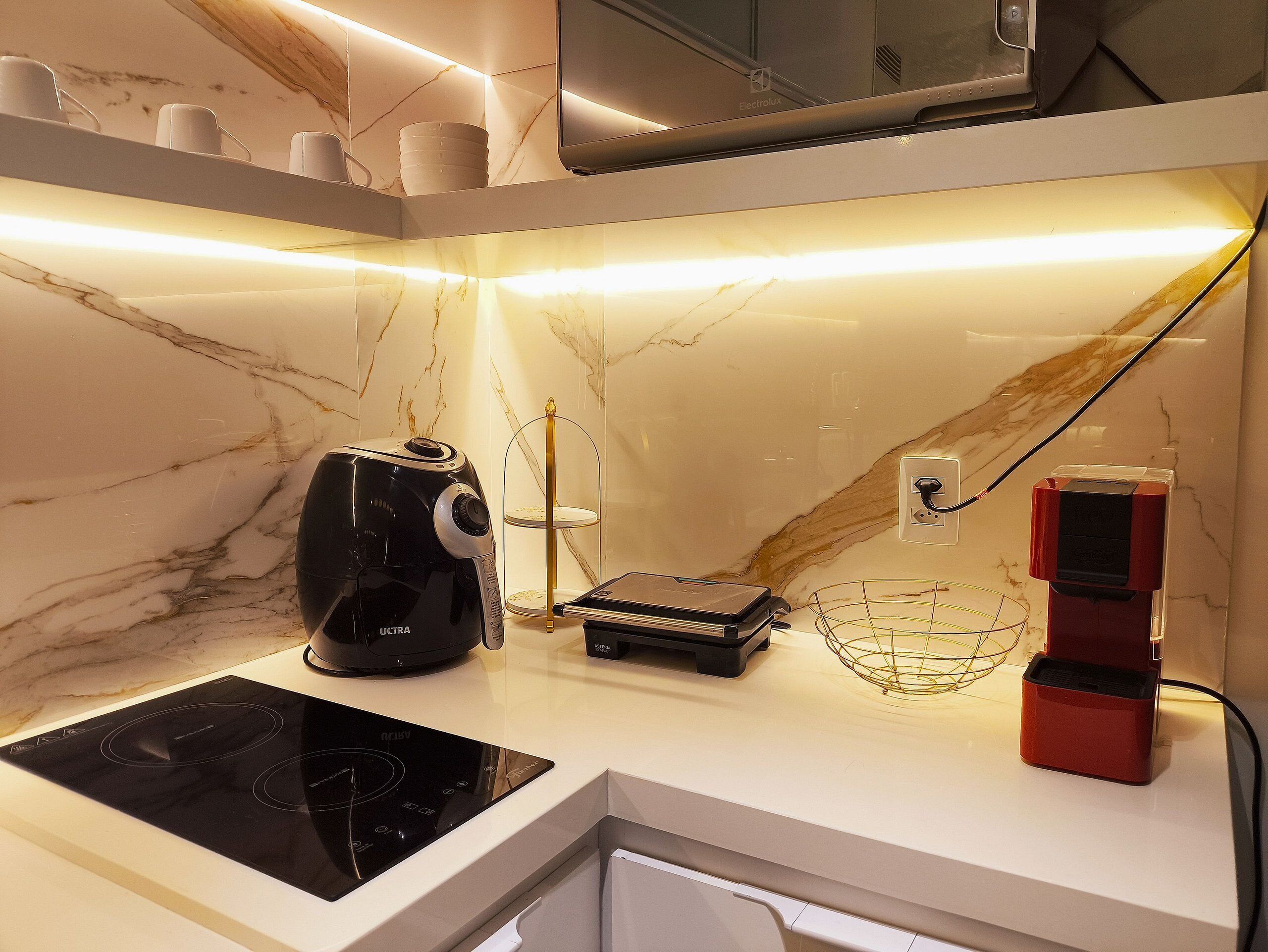 A kitchen with a black coffee maker, a small electronic scale, and a red appliance on the counter.