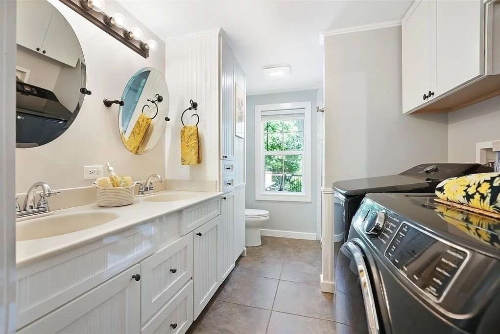 A modern bathroom with a double sink vanity, a large mirror, and a built-in stove.
