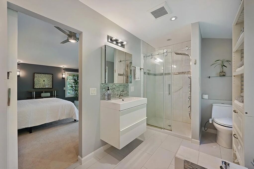 Une salle de bain moderne avec une douche à parois de verre, un meuble-lavabo blanc et un grand miroir.