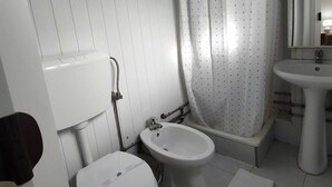Ein kleines, weißes Badezimmer mit Toilette, Bidet und Waschbecken.