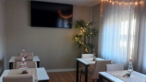 Ein Essbereich mit vier gedeckten Tischen, einem Weihnachtsbaum und einem an der Wand befestigten Fernseher.