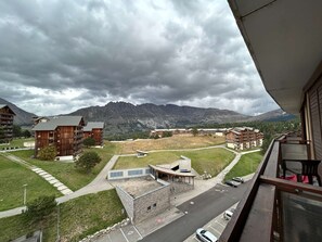 A view of a mountain resort with wooden buildings, a parking area, and a clear path leading to a building with a modern entrance. - Cozy studio for 4, 50m to slopes, Wifi, pets allowed (Le Dévoluy)