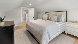 A bedroom with a large bed, a nightstand, a dresser, and a potted plant. - 2 Bed, 1.5 Bath Stunning Apartment, Central Andover Location (Andover)