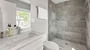 A modern bathroom with a large mirror, two sinks, a toilet, and a walk-in shower with grey tiles. - 2 Bed, 1.5 Bath Stunning Apartment, Central Andover Location (Andover)
