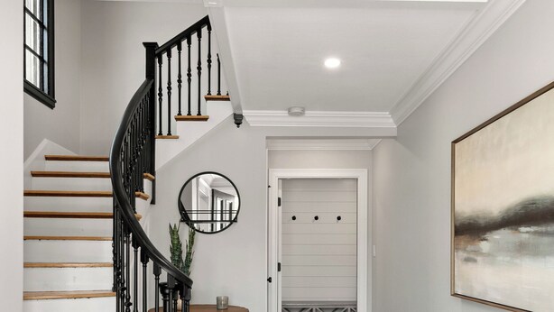 A staircase with wooden steps and black railings, a round mirror on the wall, and a painting on the right. - 2 Bed, 1.5 Bath Stunning Apartment, Central Andover Location (Andover)