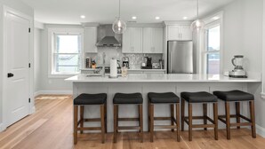 A modern kitchen with white cabinets, a large island with bar stools, stainless steel appliances, and pendant lighting. - 2 Bed, 1.5 Bath Stunning Apartment, Central Andover Location (Andover)