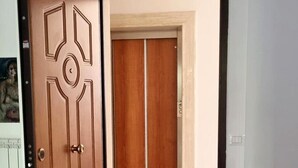 Una habitación con puerta de madera, una mesa con diseño y vista a otra habitación con puerta de madera.