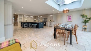 A spacious kitchen with a central island, a dining area with a table set for six, and a skylight above the kitchen. - Legoland Basecamp | Perfect for Families | Sleeps 15 (Windsor)