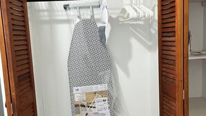 A small, enclosed closet with a wooden door, a hanging rack, and a storage shelf.