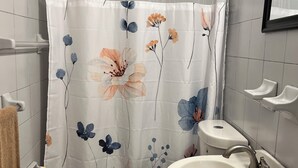 A bathroom with a shower curtain featuring floral designs, a toilet, a sink, and a towel rack.